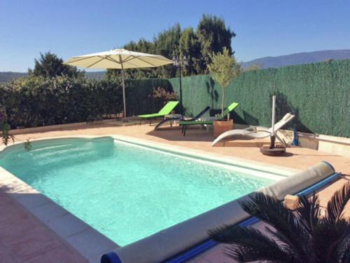 uma piscina com um guarda-sol, uma mesa e cadeiras em Tasteful Villa in Montauroux with Private Pool em Montauroux