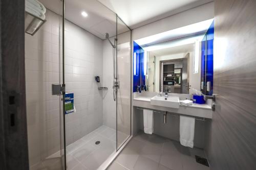 a bathroom with a shower and a sink and a mirror at Park Inn by Radisson Abu Dhabi Yas Island in Abu Dhabi