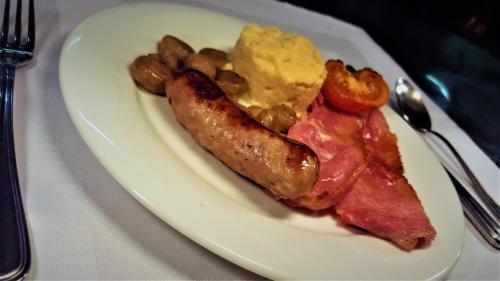 a plate of food with bacon sausage and potatoes at Marygreen Manor in Brentwood
