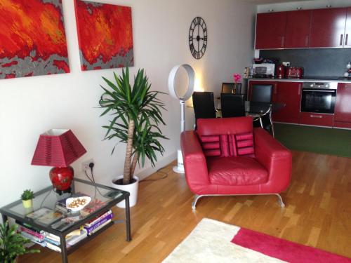 a living room with a red chair and a table at Stunning Spacious City Apartment with free parking in Cardiff