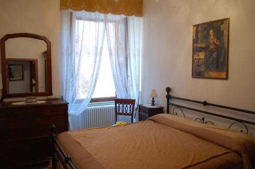 1 dormitorio con cama, espejo y ventana en Affittacamere Le Fonti, en Arcidosso