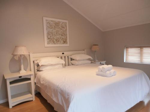 Un dormitorio con una cama blanca con toallas. en 75 The Dunes, en Plettenberg Bay