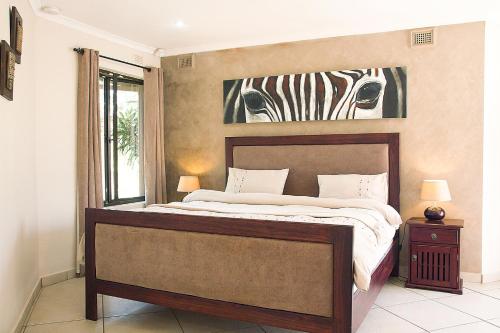 a bedroom with a bed with a zebra picture on the wall at Matusadona Guest Lodge in Hillcrest