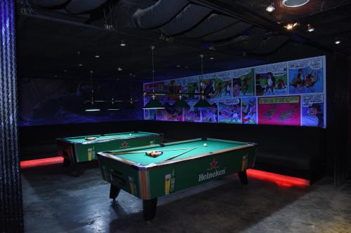two pool tables in a room with a wall with posters at Monroe Hotel & Suites in Manama