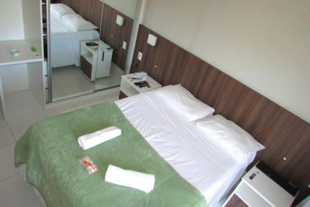 a bedroom with a bed with green sheets and a mirror at AP Beira da Lagoa da Conceição in Florianópolis