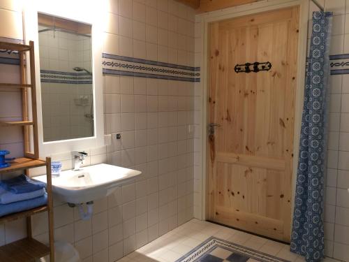 een badkamer met een wastafel en een houten deur bij Elferink Hoeve in Woudenberg