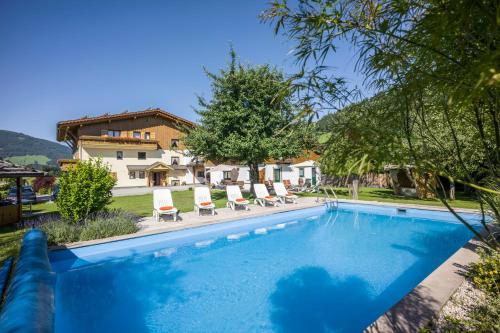 a pool with chairs and a house in the background at Pension Sonnblick in Westendorf