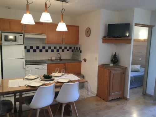 a kitchen with a wooden table and white chairs at Appartement Les Pics d'Aran in Luchon