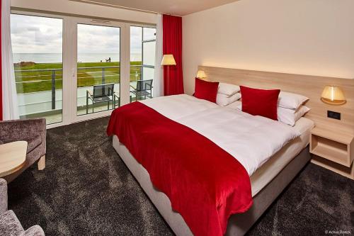 a bedroom with a large bed with a red blanket at Hotel Schelf GmbH & Co. KG in Büsum