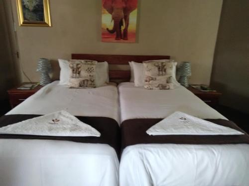 two beds in a room with white sheets and pillows at Noma-Nini Lodge in White River