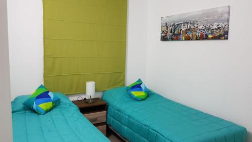 2 camas en una habitación con sábanas verdes y almohadas azules en Perla del Elqui Pacifico, en La Serena