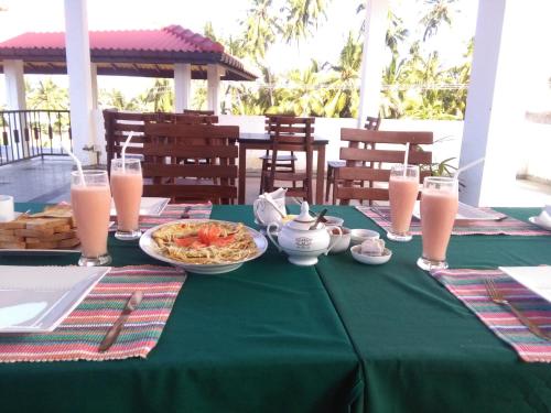 Sanras Hotel and Restaurant في غالي: طاولة خضراء مع طبق من المواد الغذائية والمشروبات
