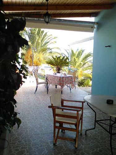 a patio with a table and chairs and palm trees at Villa Castle Sea View in Paralion astros
