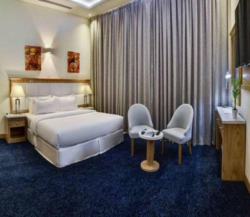 um quarto de hotel com uma cama, uma mesa e cadeiras em Golden Dune Hotel AlFayhaa em Riyadh