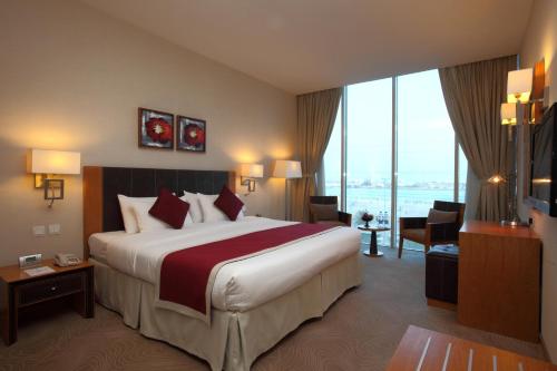 a hotel room with a bed and a large window at Mena Hotel Al Jubail in Al Jubail