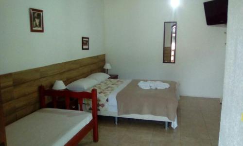 1 dormitorio con 2 camas, silla y ventana en Tarkna - Hotel Holandês en Teresópolis
