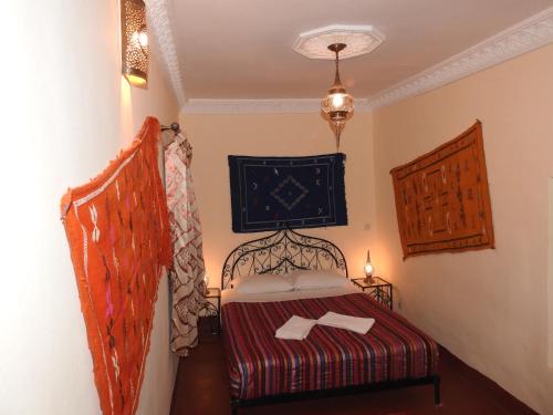 een kleine slaapkamer met een bed met een rode deken bij Cinema Riad in Ouarzazate