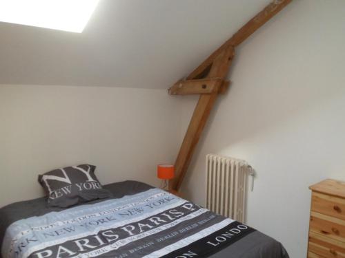 1 dormitorio con 1 cama y una escalera de madera en la pared en L'etape de St Hilaire La Gravelle, en Saint-Hilaire-la-Gravelle