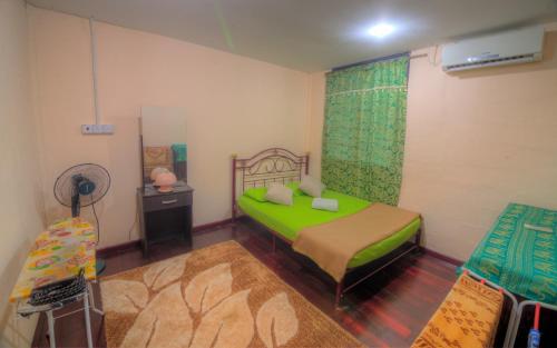 a bedroom with a green bed and a mirror at Budget Umi Homestay Kuching in Kuching