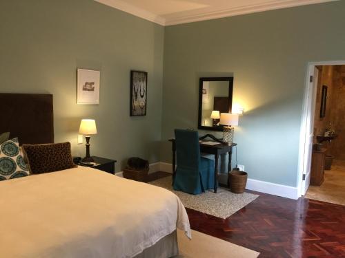 a bedroom with a bed and a desk and a mirror at The Parkwood in Johannesburg