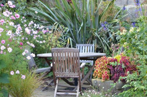 two chairs and a table in a garden with flowers at Gravetye Manor in East Grinstead