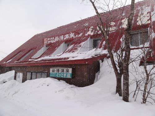 a red building with a sign on it in the snow at Shinyu Onsen Kurikomaso in Kurihara