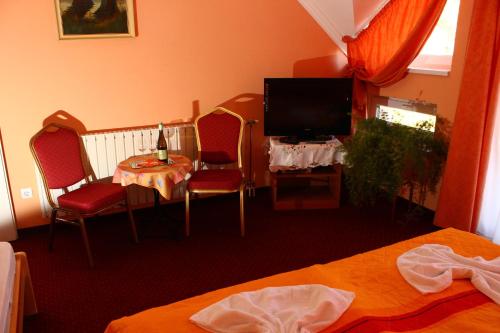 a hotel room with a television and a table and chairs at Kálmán Panzió in Szeged