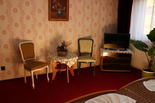 a room with two chairs and a table and a television at Kálmán Panzió in Szeged