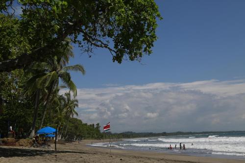 a beach with a bunch of people and the ocean at Palm Coast Luxury Rentals in Esterillos Este