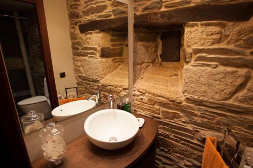 baño con 2 lavabos y pared de piedra en Casa Do Bosque, en Sarria