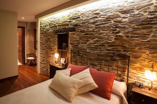 1 dormitorio con pared de piedra y 1 cama con almohadas en Casa Do Bosque en Sarria