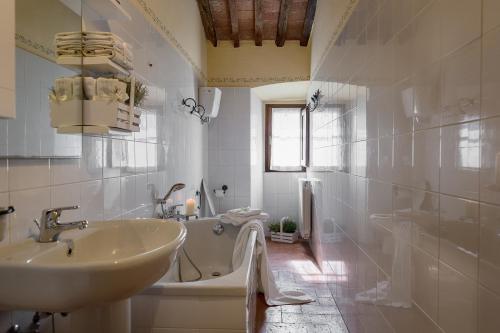 a white bathroom with a sink and a tub at Villa Fontocchio in Cortona