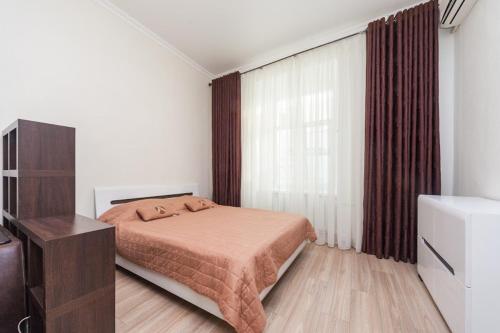 a bedroom with a bed and a dresser and a window at center, Apartment on Deribasovskaya 10 in Odesa