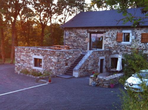 a stone house with a car parked in front of it at Aux Pays Des Sucs in Saint-Hostien