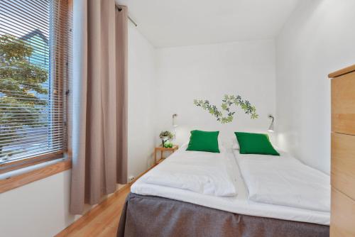 a bedroom with a bed with green pillows and a window at Frogner House - Fiskepiren in Stavanger