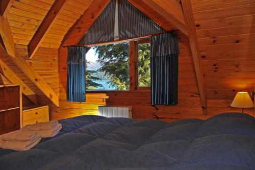 ein Schlafzimmer mit einem Bett und einem Fenster in einer Hütte in der Unterkunft Paisaje Bandurrias in Villa La Angostura