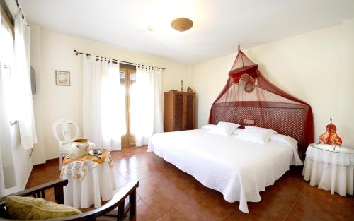 Schlafzimmer mit einem großen weißen Bett mit einem Kopfteil aus Holz in der Unterkunft Hotel Boutique Alicia Carolina in Monachil
