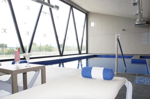 a swimming pool with a chair and a table in a room at La Quinta by Wyndham San Jose Chiapa Puebla in San José Chiapa