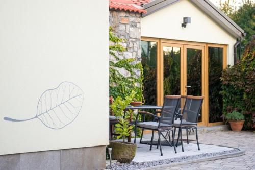 a patio with chairs and a leaf painted on a wall at Zenja Apartments - Property with Cozy Garden & Free Private Parking in Divača