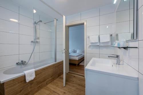 a white bathroom with a tub and a sink at Parkhotel Atlantic in Heidelberg