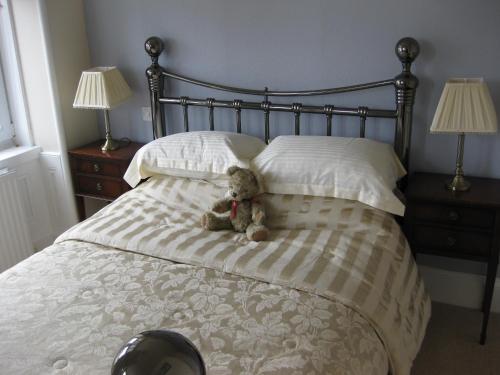 a bed with two pillows and a stuffed animal on the headboard at Struan House in Buckie