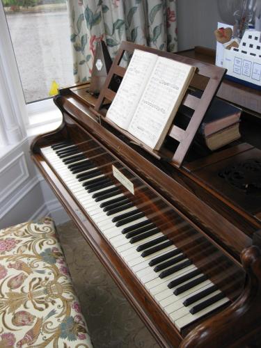 een houten piano in een kamer met een raam bij Struan House in Buckie