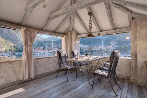 a dining room with a table and chairs and windows at Kotor old town Palace Bucha in Kotor