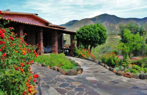 a large stone building with a flower garden in front of it at Quinta Maria en la Ruta del Vino in Valle de Guadalupe