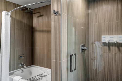 a bathroom with a tub and a shower with a glass door at Hotel Arts Kensington in Calgary
