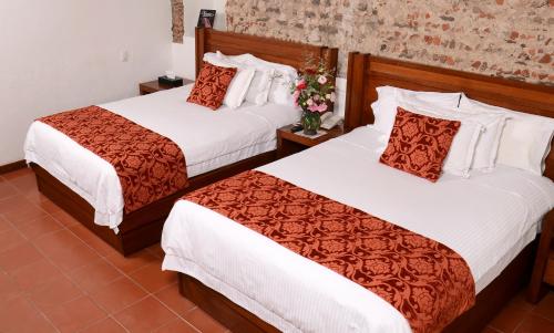 two beds in a hotel room with flowers at El Serafin Hotel Boutique in Querétaro