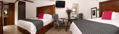 a hotel room with two beds and a table at El Serafin Hotel Boutique in Querétaro