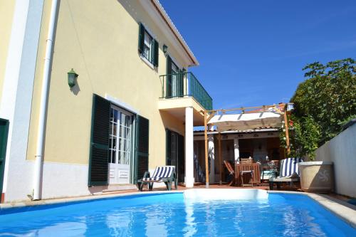a swimming pool in front of a house at Yellow House Ericeira in Santo Isidoro