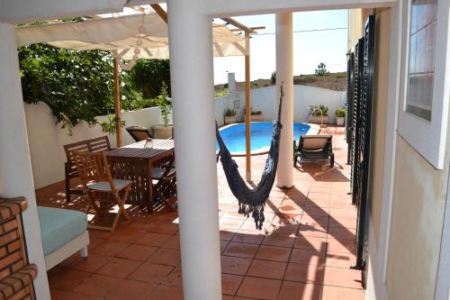 a patio with a hammock and a swimming pool at Yellow House Ericeira in Santo Isidoro