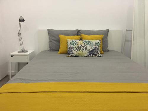 ein Bett mit gelben und grauen Kissen in einem Schlafzimmer in der Unterkunft Lisboa Comfort Apartment in Lissabon